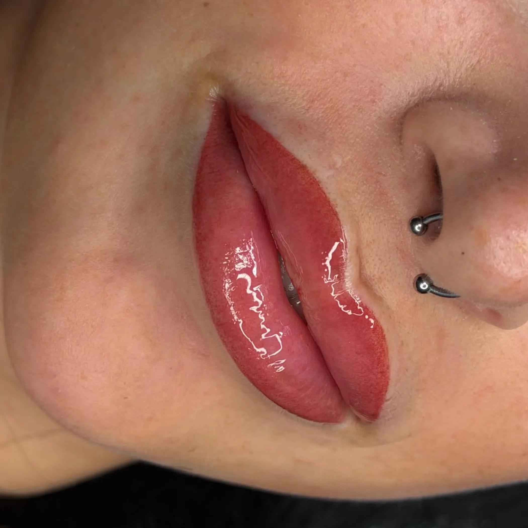 woman applying balm to lip tattoo